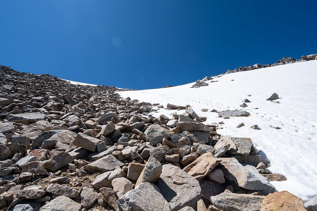 After emerging from the boulder field on the east side of the natural ramp I went below the large snow patch, up the left side of if, then diagonally back towards the summit through a gap in the snow above it. Those are not my footprints.